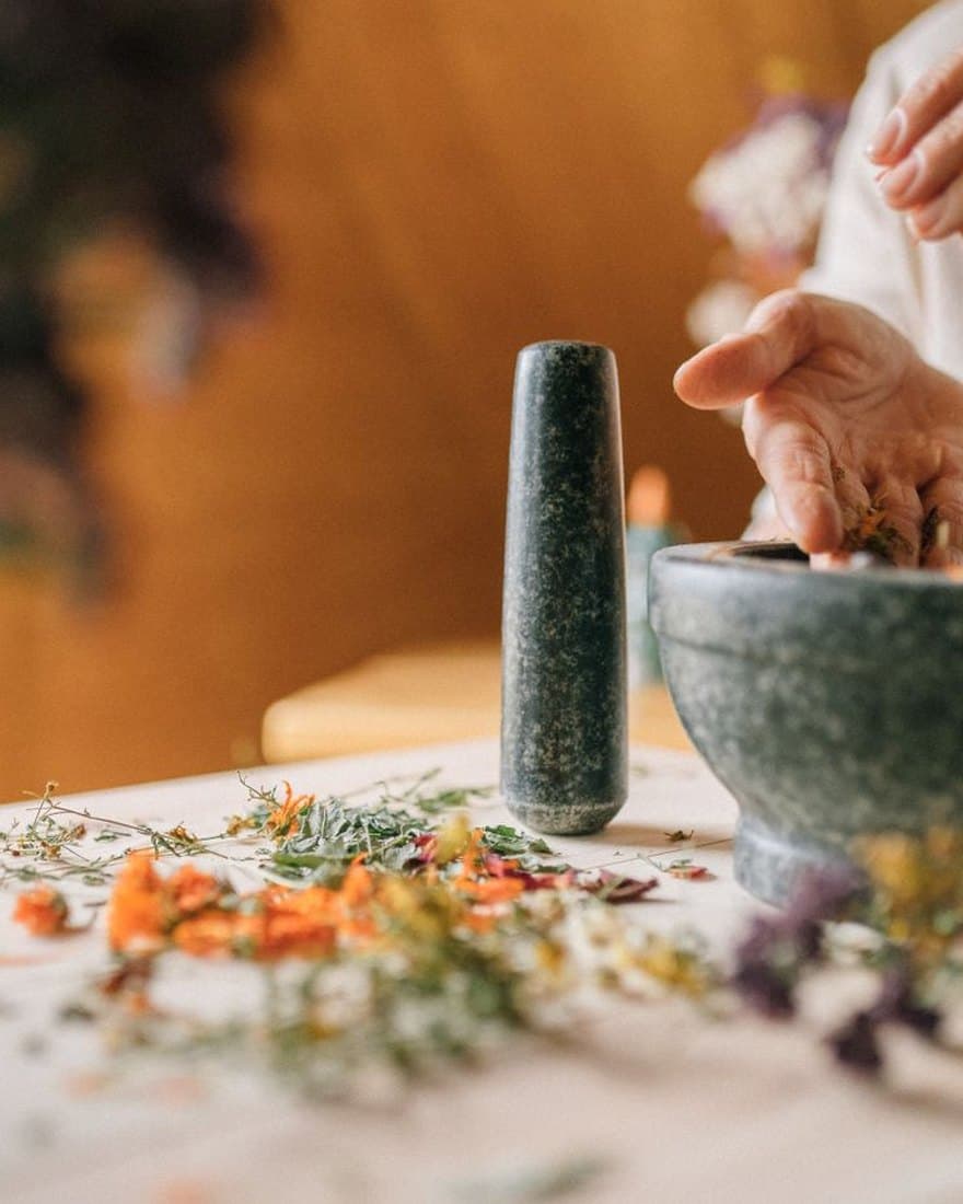 Mains préparant un mélange de plantes séchées dans un mortier