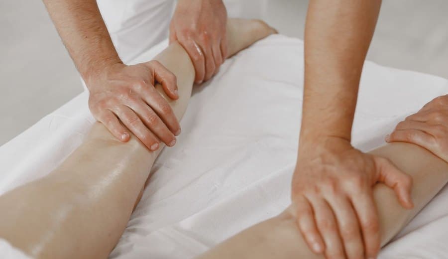 Mains effectuant un drainage lymphatique sur une jambe